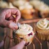 person holding cupcake with white icing on top