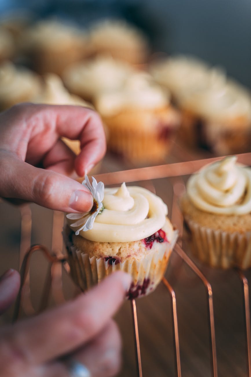 person holding cupcake with white icing on top