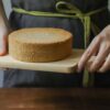 person holding chopping board with sponge cake