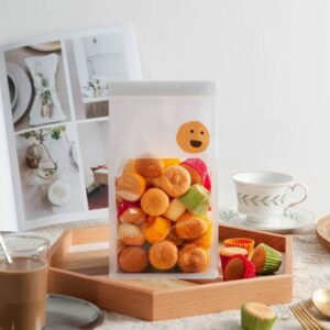 Sachet transparent contenant des mini-biscuits colorés sur une table avec tasse de thé.